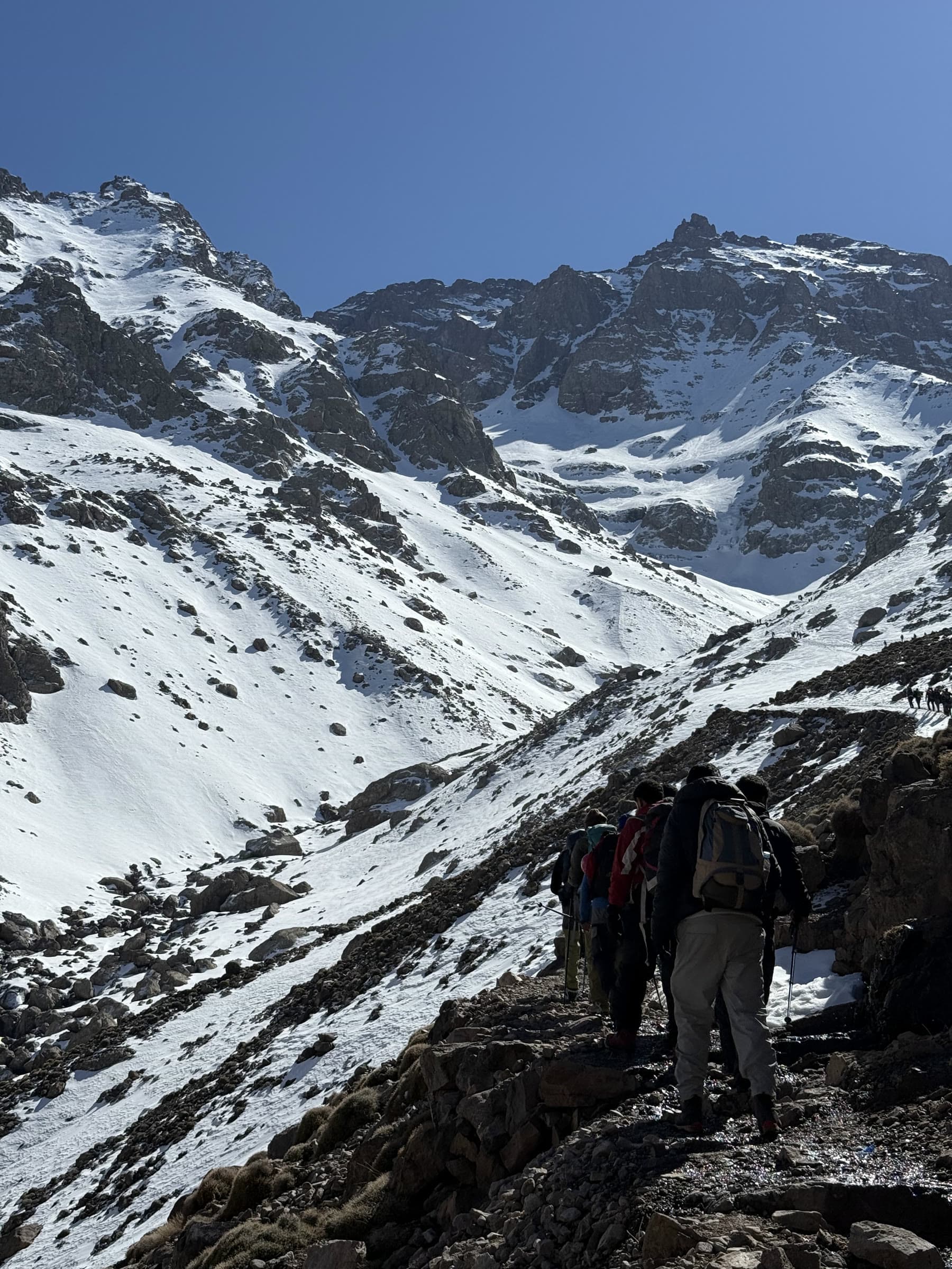 Walkers on the trail below the snow-filled south cwm, the ridge line high above them