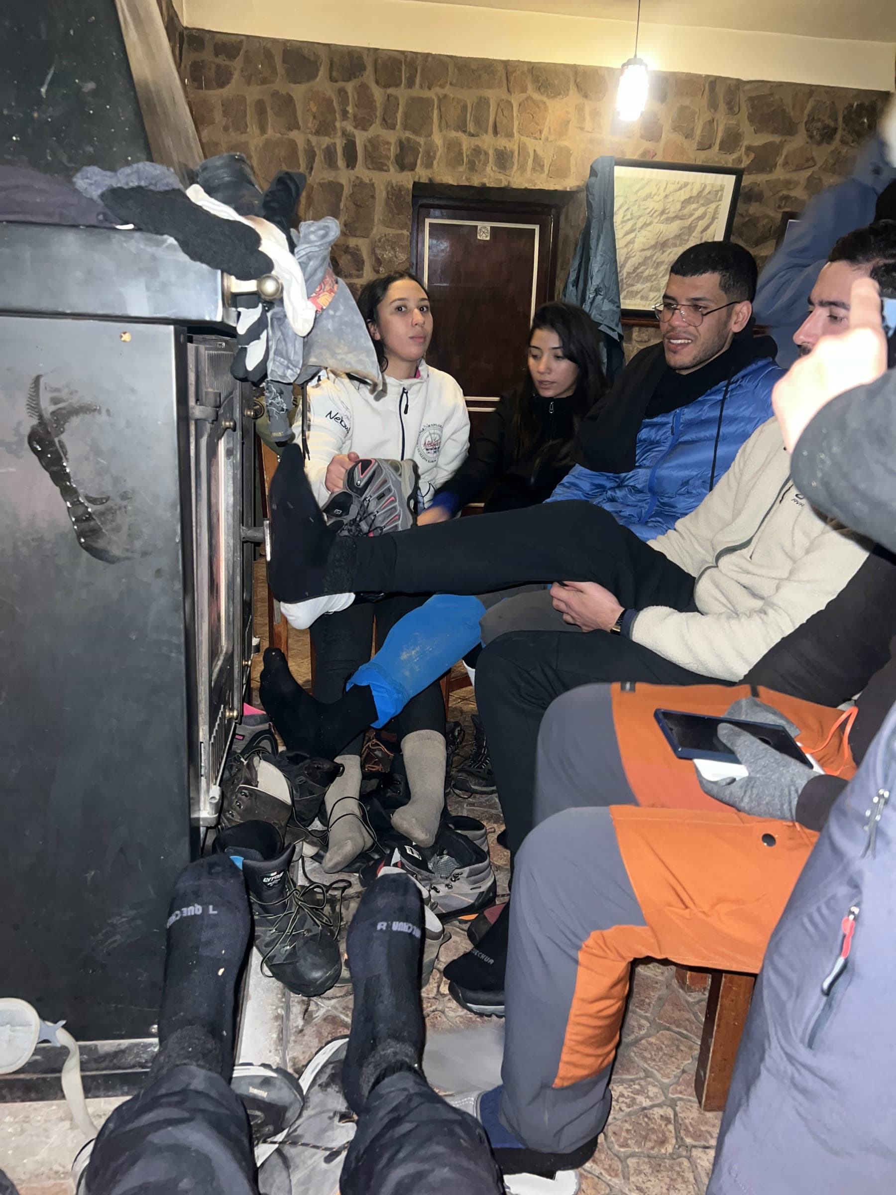 Walkers round a wood stove with boots off and gloves drying on the flue